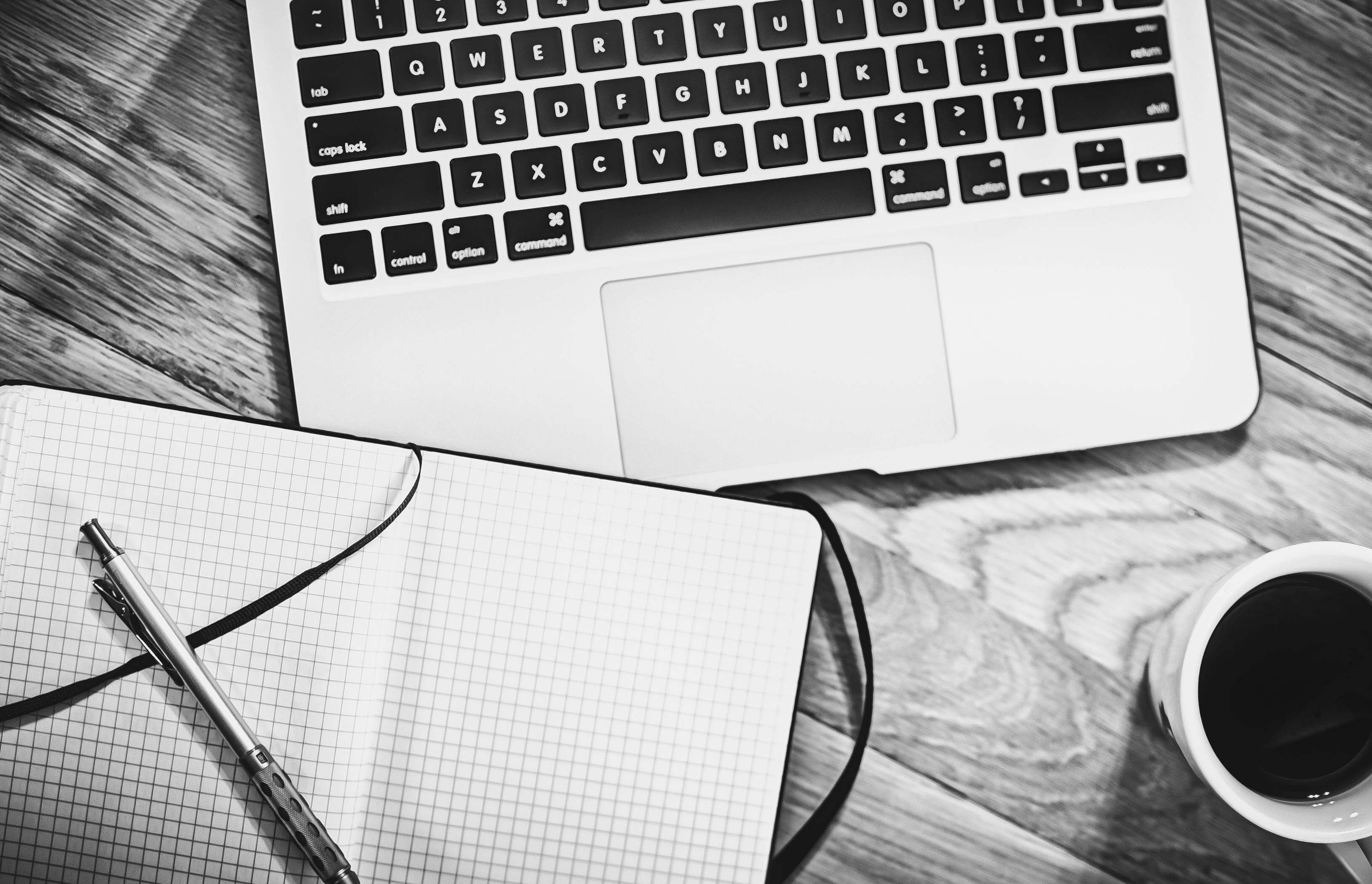 Photo of a Macbook and a notepad